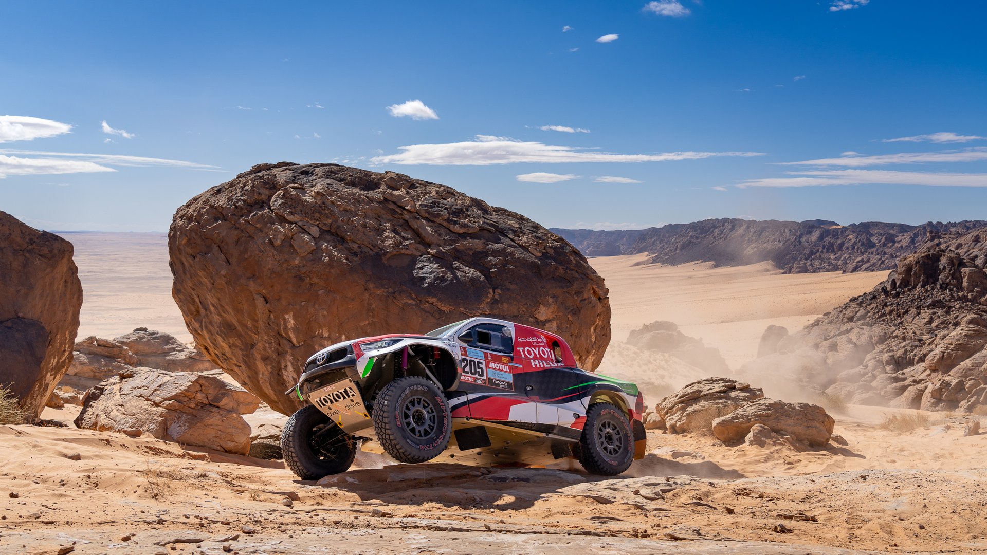 Rally car launching off rocks in the Saudi desert at the Dakar